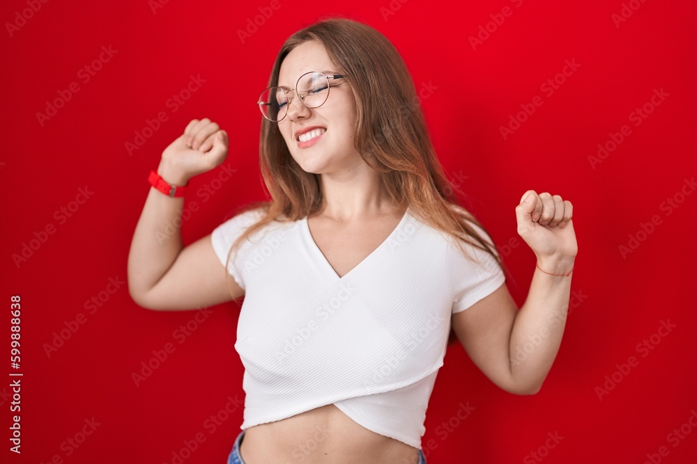 Sticker Young caucasian woman standing over red background stretching back, tired and relaxed, sleepy and yawning for early morning