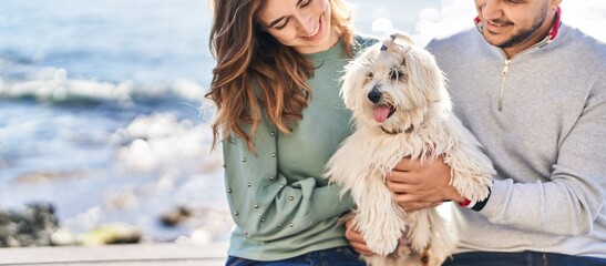 Man and woman holding dog hugging each other at seaside