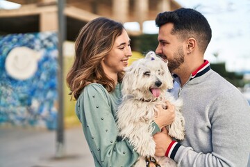 Man and woman holding dog standing together at street