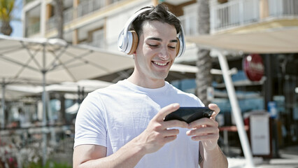 Young hispanic man smiling confident watching video on smartphone at coffee shop terrace