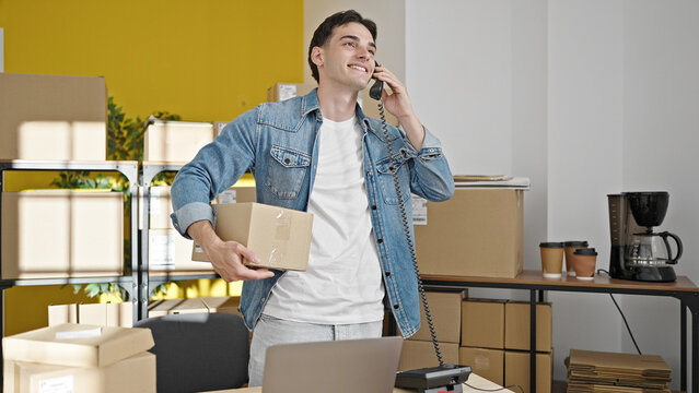 Young hispanic man ecommerce business worker talking on telephone holding package at office