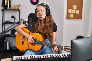 Young beautiful hispanic woman musician singng song playing classical guitar at music studio