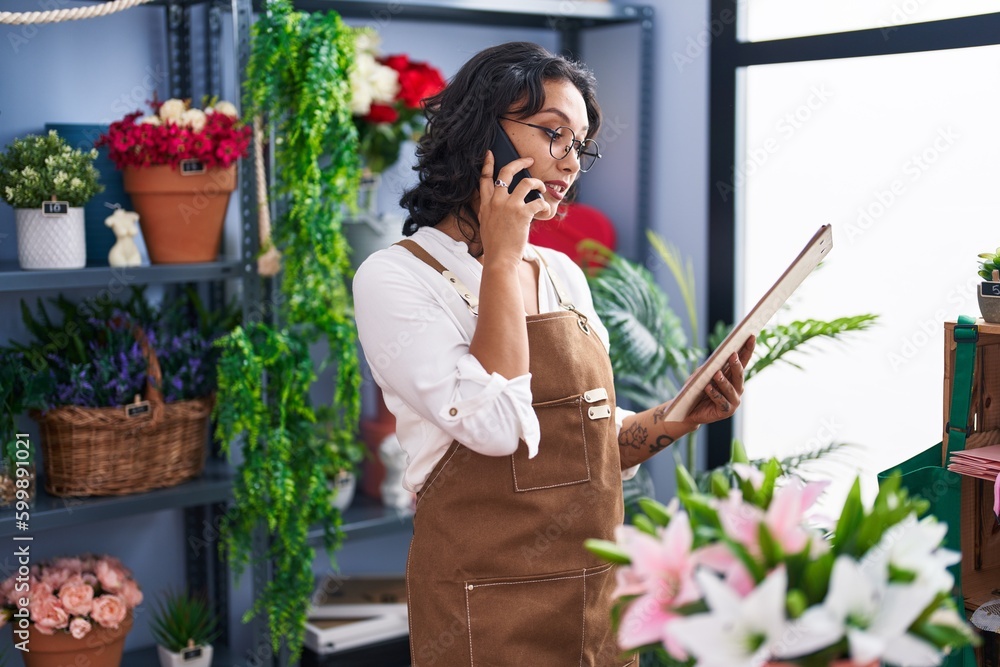 Sticker young beautiful hispanic woman florist talking on smartphone reading clipboard at flower shop