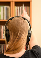 Kobieta z blond włosami z słuchawkami na uszach stojącą przy płytach cd - obrazy, fototapety, plakaty