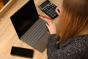 Kobieta siedząca przy biurku przy laptopie - obrazy, fototapety, plakaty