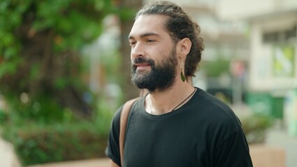 Young hispanic man looking to the side with serious expression at park