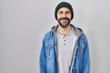 Young hispanic man with tattoos wearing wool cap with a happy and cool smile on face. lucky person.