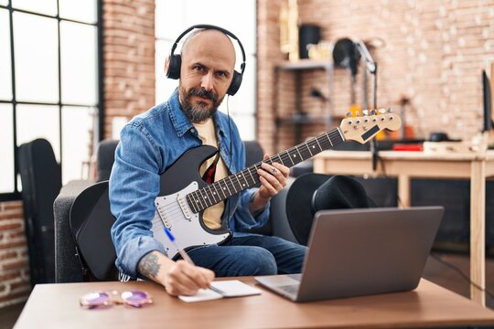 Young bald man musician composing song at music studio
