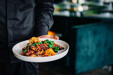 chef hand hold plate whith Stewed pork slice with noodles and vegetables