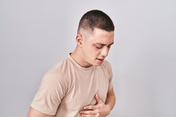 Young man standing over isolated background with hand on stomach because indigestion, painful...