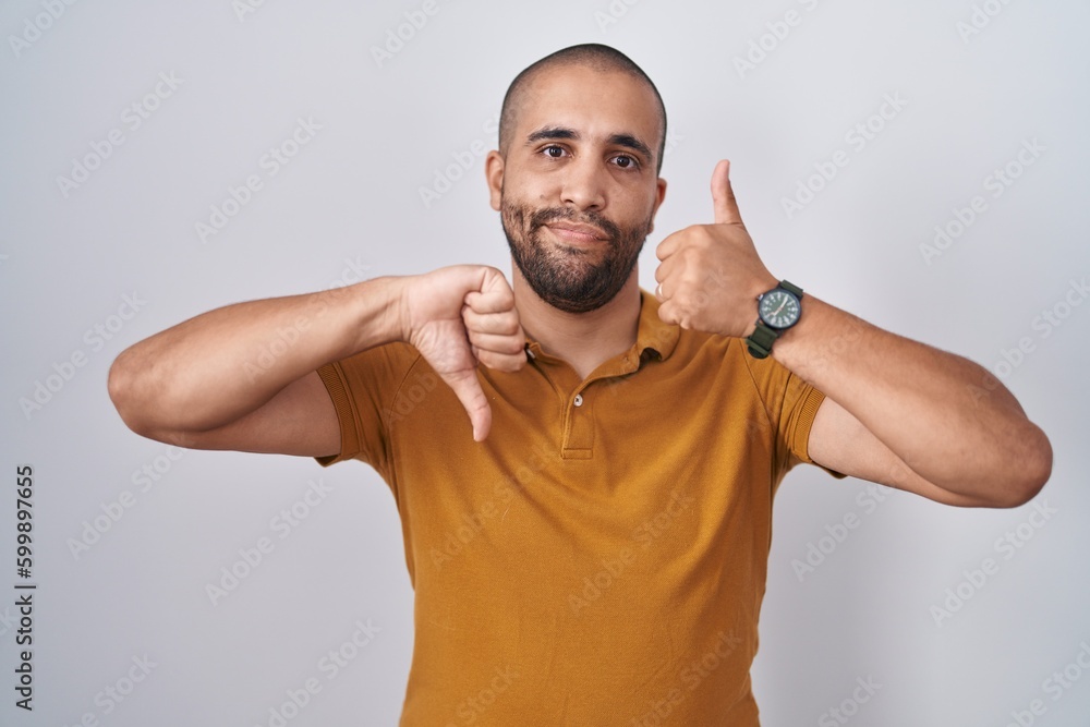 Canvas Prints Hispanic man with beard standing over white background doing thumbs up and down, disagreement and agreement expression. crazy conflict