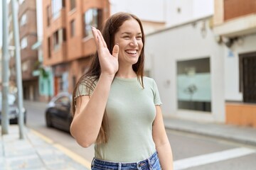 Young beautiful woman smiling confident saying hello with hand at street © Krakenimages.com
