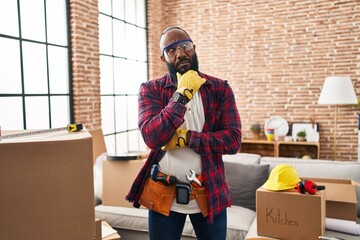 African american man working at home renovation serious face thinking about question with hand on...