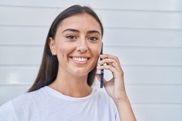 Young beautiful hispanic woman smiling confident talking on the smartphone over isolated white background