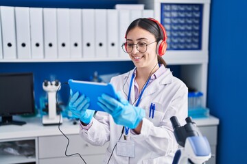 Young hispanic woman scientist watching video on touchpad at laboratory