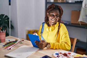 African american woman artist smiling confident drawing on touchpad at art studio