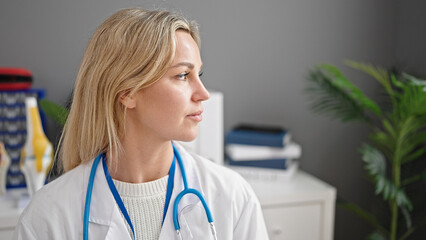 Young blonde woman doctor standing with serious expression at clinic