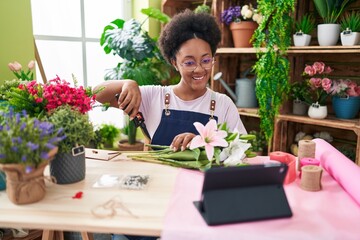 African american woman florist make bouquet of flowers watching video on touchpad at flower shop