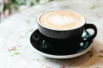 Cup with hot tasty coffee on white table in cafe, close up view