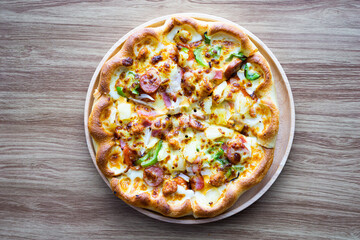 Supreme or deluxe pizza on round plate and wood background, middle on frame