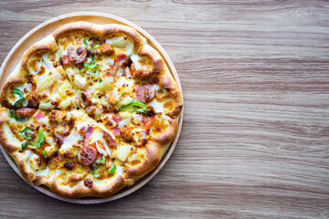 Supreme or deluxe pizza on round plate and wood background, left on frame, copy space on right