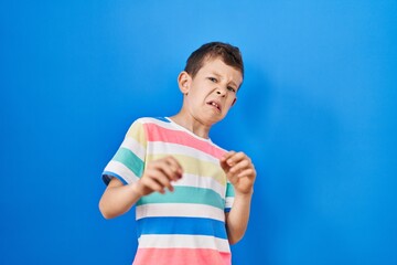 Young caucasian kid standing over blue background disgusted expression, displeased and fearful...