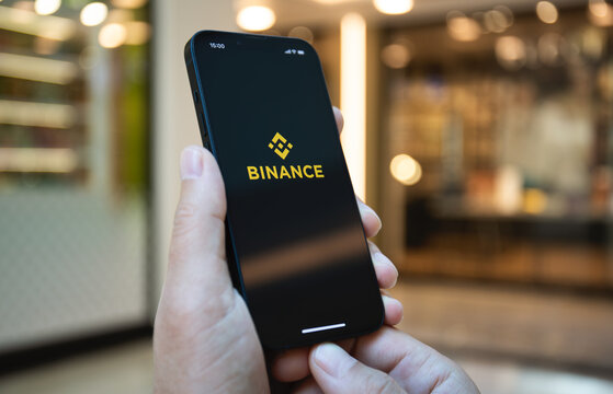 Man hand holding iPhone 14 with app cryptocurrency exchange Binance