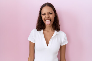 Young hispanic woman wearing casual white t shirt sticking tongue out happy with funny expression. emotion concept.