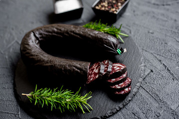 Spanish black pudding or blood sausage with rosemary on a stone background