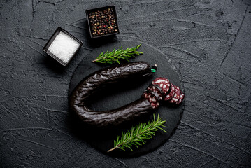 Spanish black pudding or blood sausage with rosemary on a stone background