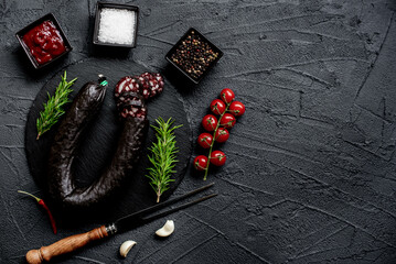 Spanish black pudding or blood sausage with rosemary on a stone background with copy space for your...