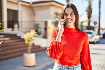 Fototapeta premium Young beautiful hispanic woman smiling confident talking on the smartphone at street
