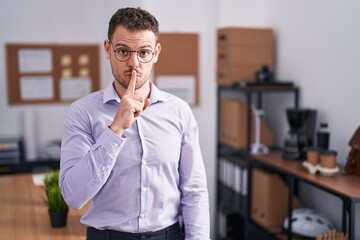 Young hispanic man at the office asking to be quiet with finger on lips. silence and secret concept.