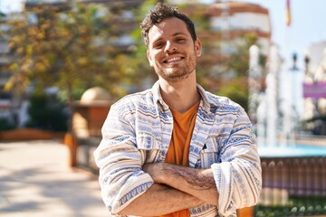 Young hispanic man smiling confident standing with arms crossed gesture at park