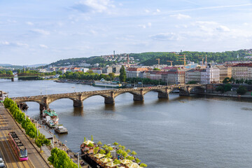 Fototapeta na wymiar Top view of the stone transport bridge over the Vltava river, traffic of cars on the bridge, old architectural buildings. Beautiful summer landscape of the city of Prague.