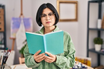 Young chinese woman artist reading book at art studio