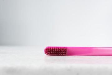 Pink toothbrush with orange bristles on a white background, pink toothbrush with copy space