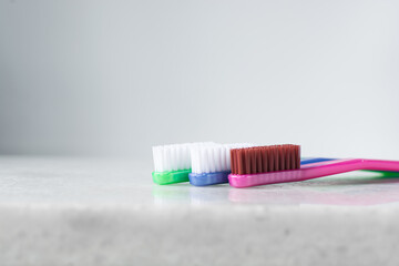 Blue, pink and green toothbrush with white bristles on a white background, colorful toothbrushes with copy space
