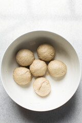 Kanelbullar dough divided into balls, Swedish cinnamon twist dough in a white bowl, process of making Swedish cinnamon buns