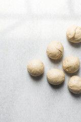 Kanelbullar dough divided into balls, Swedish cinnamon twist dough on a marble surface, process of making Swedish cinnamon buns