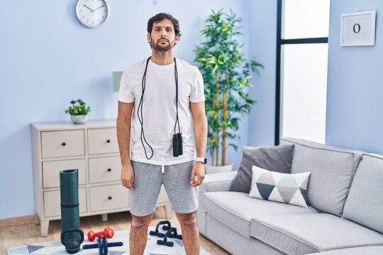 Handsome latin man wearing sportswear at home relaxed with serious expression on face. simple and natural looking at the camera.