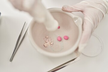 Fototapeta na wymiar Young beautiful hispanic woman scientist crushing pills on bowl at laboratory