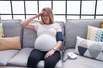 Young pregnant woman measuring pulse using tensiometer at home