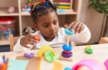 African american girl playing with hoops game sitting on table at kindergarten