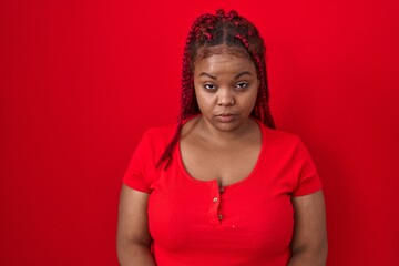 African american woman with braided hair standing over red background skeptic and nervous, frowning upset because of problem. negative person.