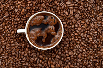 Cup of coffee and heap of fresh roasted coffee beans on the table. Close up. Top view.