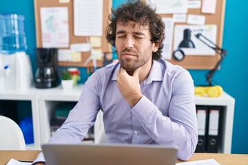 Naklejka premium Young hispanic man business worker using laptop suffering for throat pain at office