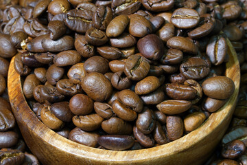 Coffee beans in a round wooden bowl close-up. Roasted aromatic coffee macro. Brown coffee background