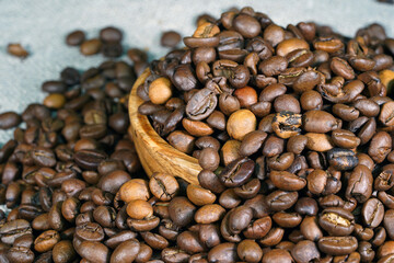 Coffee beans in a round wooden bowl close-up. Roasted aromatic coffee macro. Brown coffee background