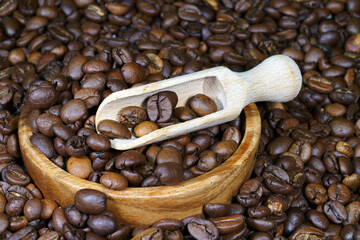 Coffee beans in a round wooden bowl close-up. Roasted aromatic coffee macro. Brown coffee background